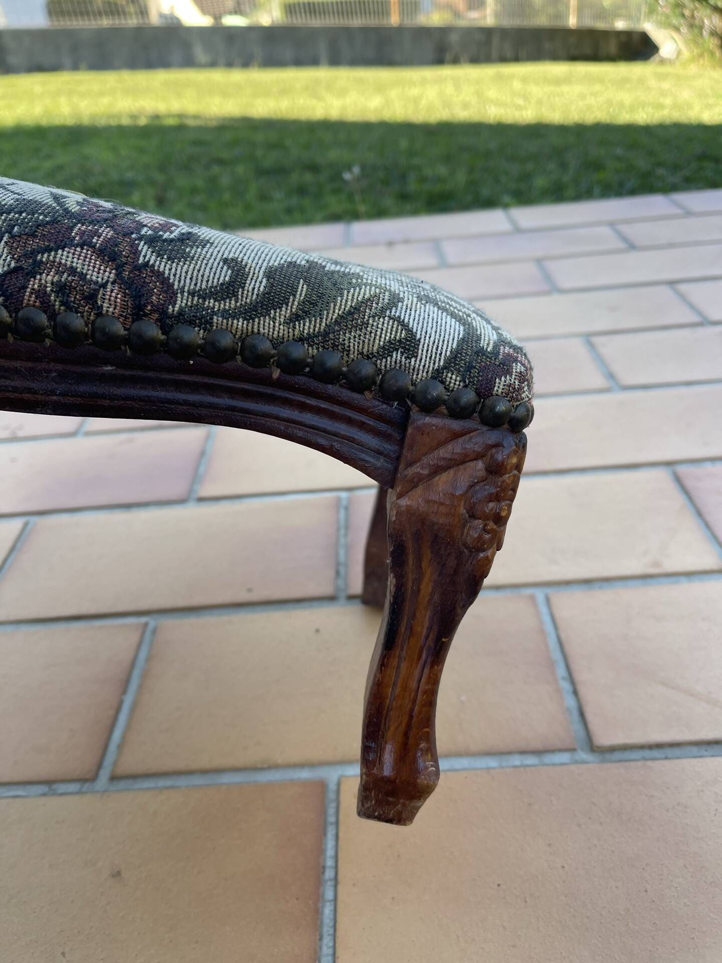 Antique wooden footstool with hand-carved details and floral upholstery –