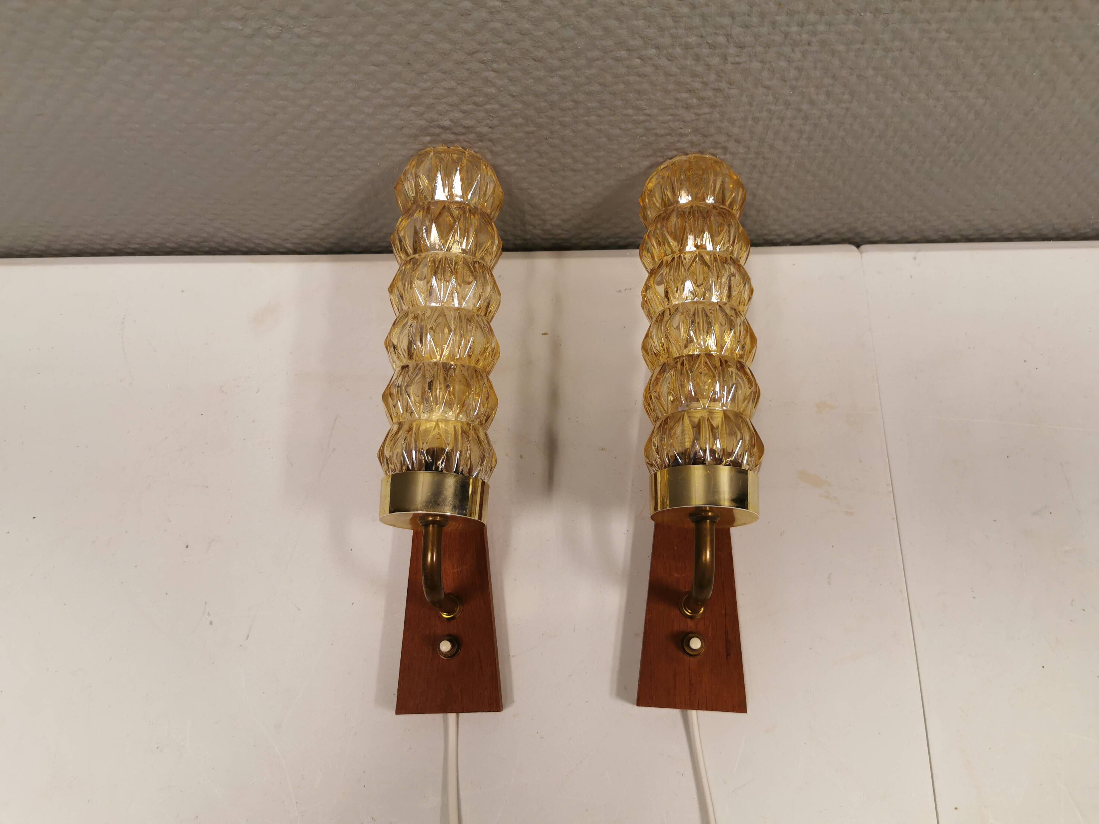 A set of Danish wall lights in champagne coloured glass with brass and teak.