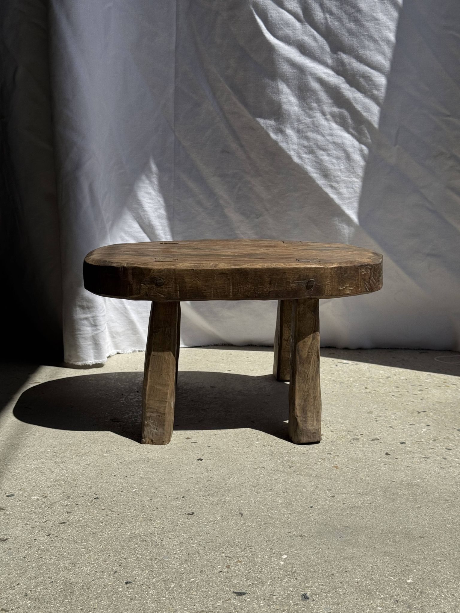 Small stool, oval solid teak side table with curved legs in wabi-sabi style.