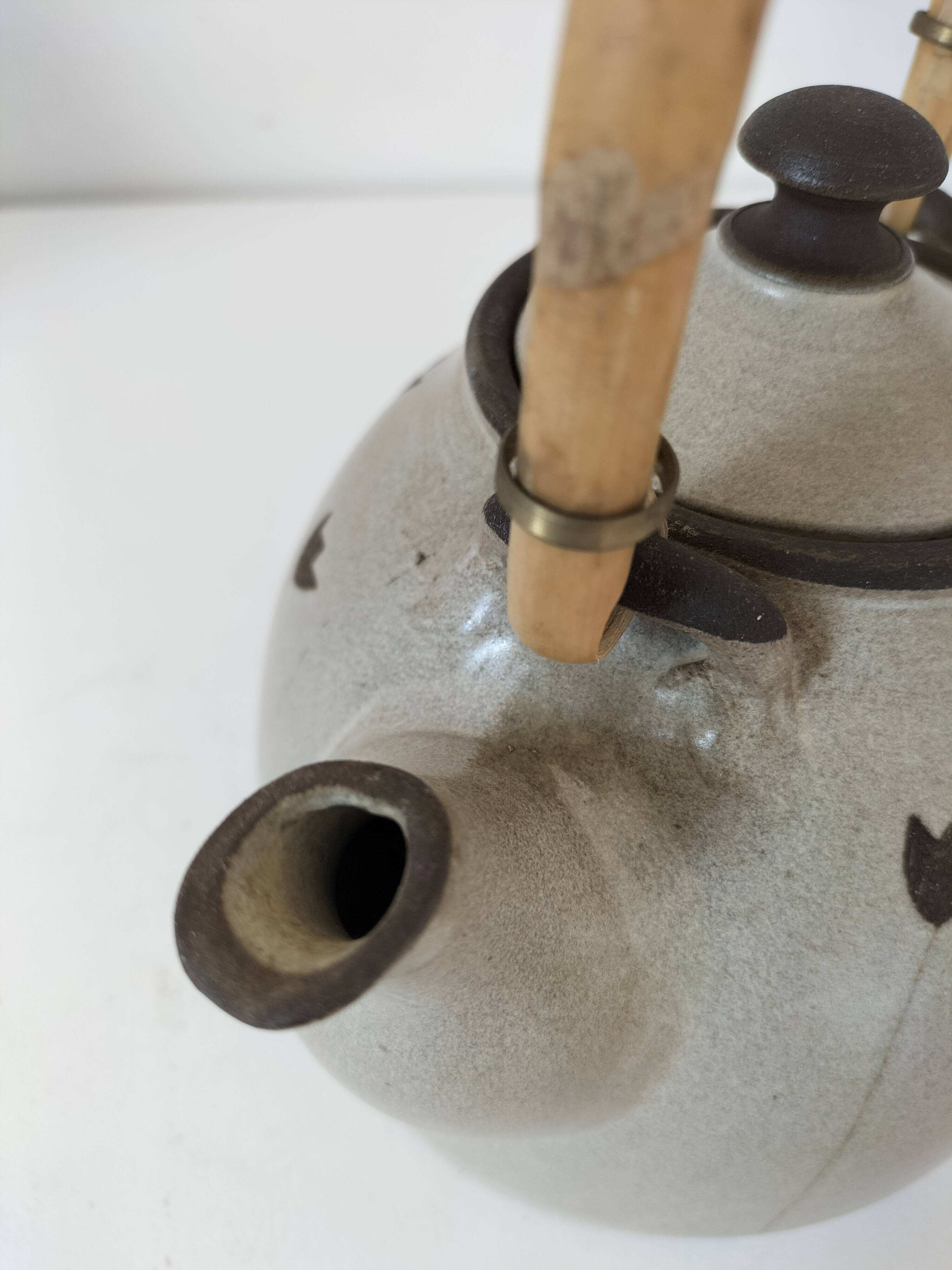 Beige stoneware teapot with stylized flowers and rattan handle