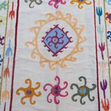 White suzani kilim rug with multi-colored embroidered patterns