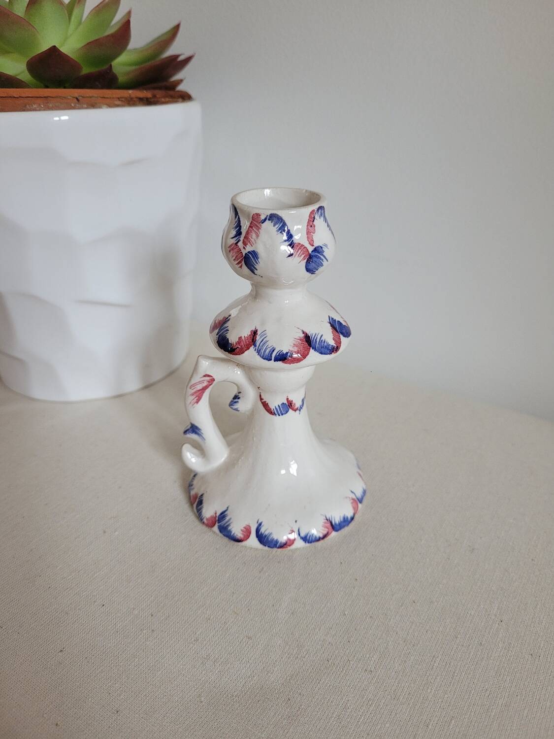 Ceramic candlestick with red and blue decoration.