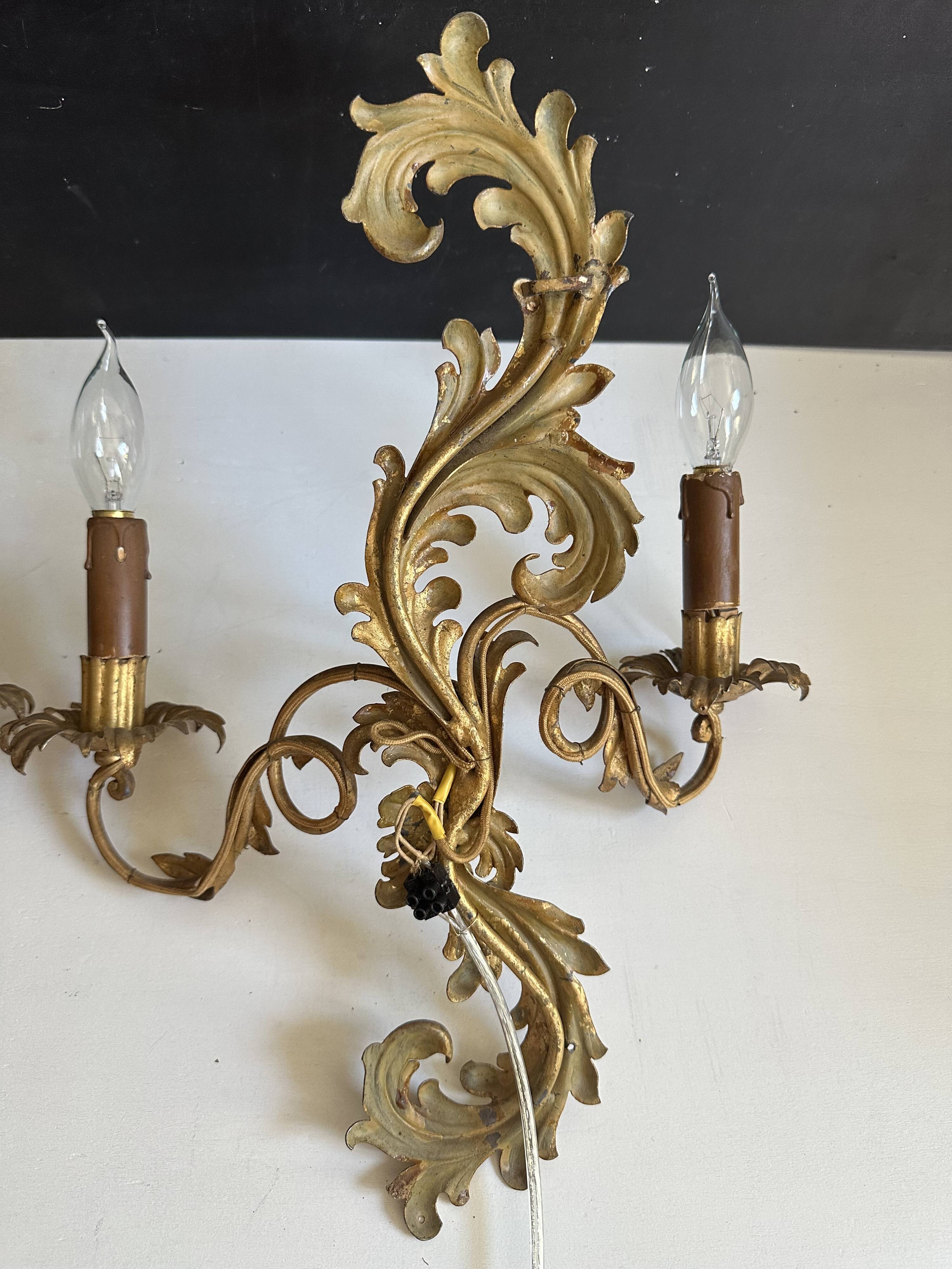 Pair of Italian Hollywood Regency wall lights in iron and gilded sheet metal.
