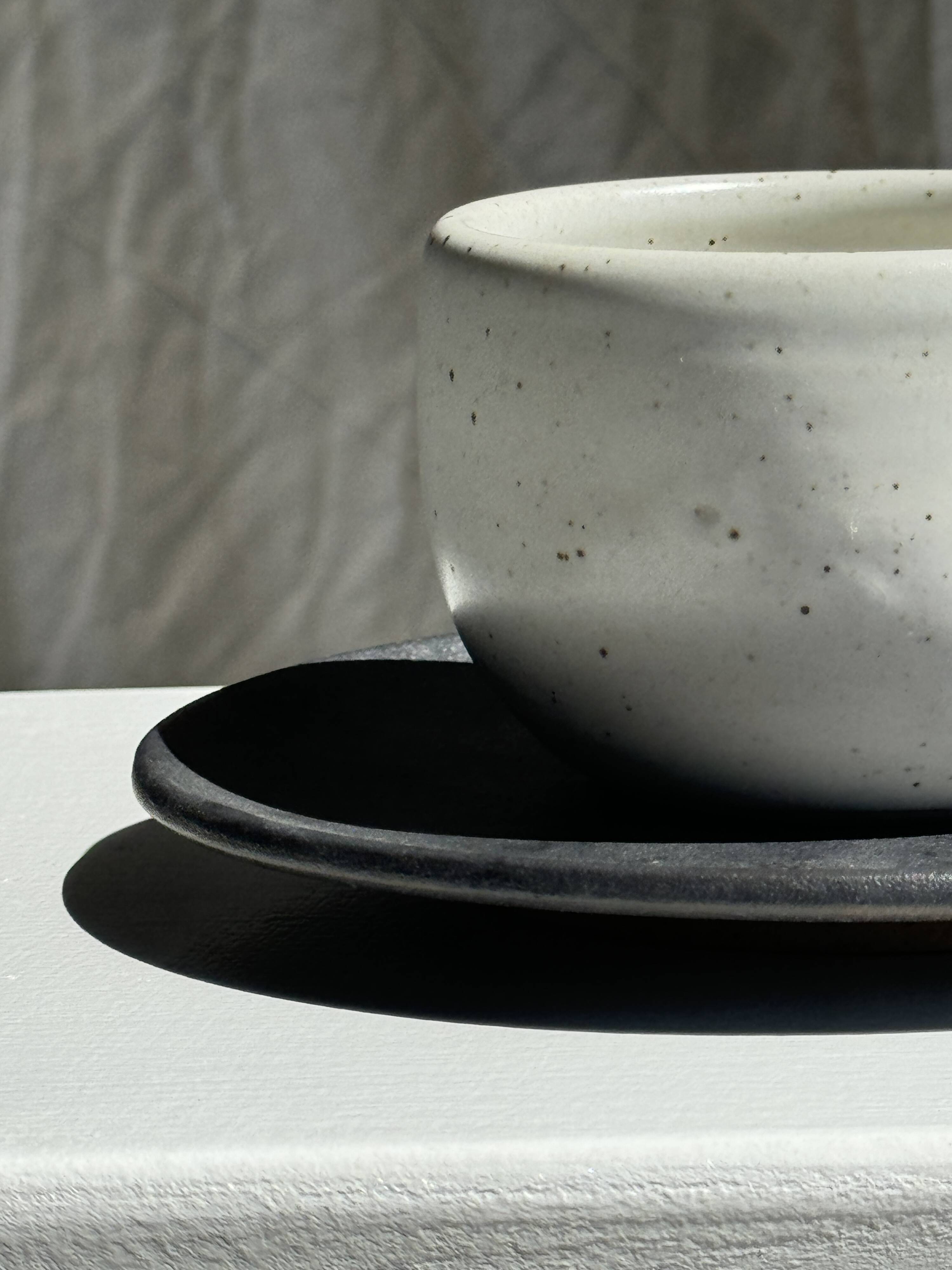 White Indonesian ceramic cup and gray saucer