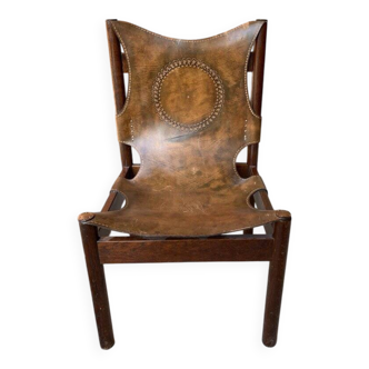 Handcrafted brown leather armchair (1970s) with a circular pattern and wooden frame.