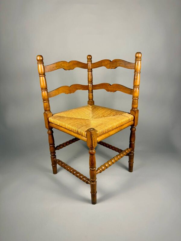 Chaise d'angle vintage en bois avec assise en paille tissée.