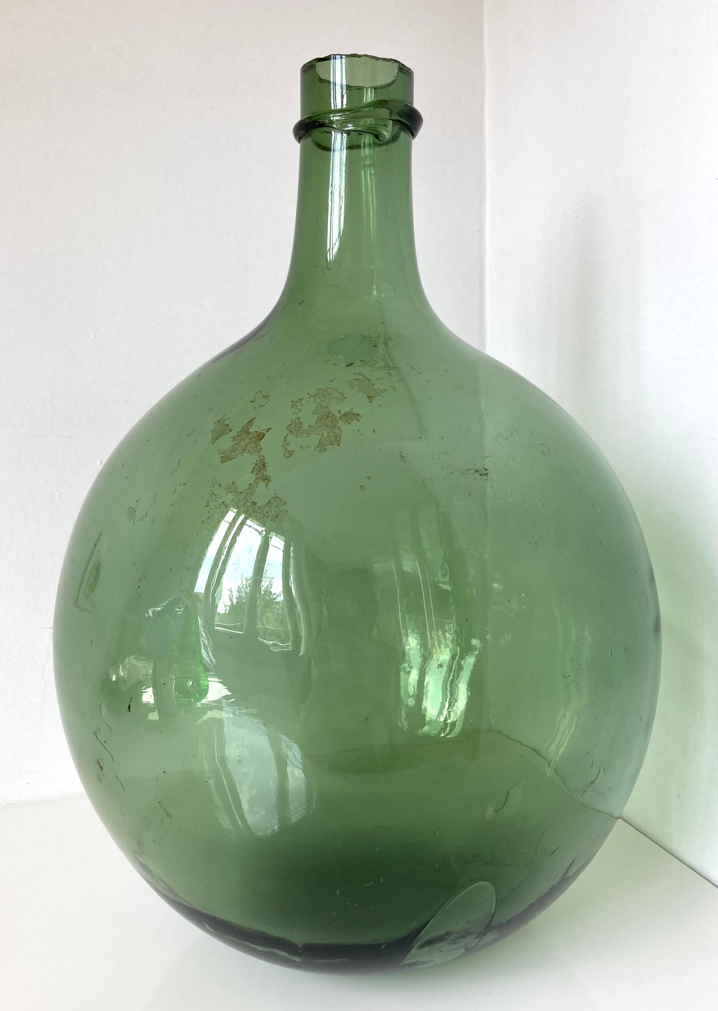 Old demijohn in green glass with ringed neck and hammered opening