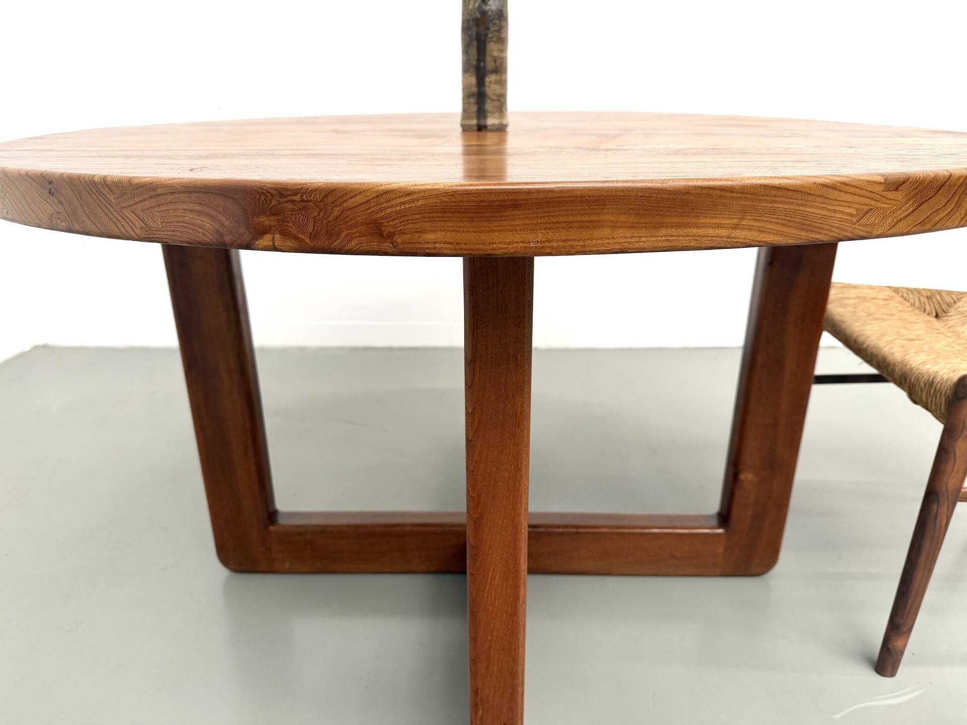 Modernist round table in solid elm, crossed legs.