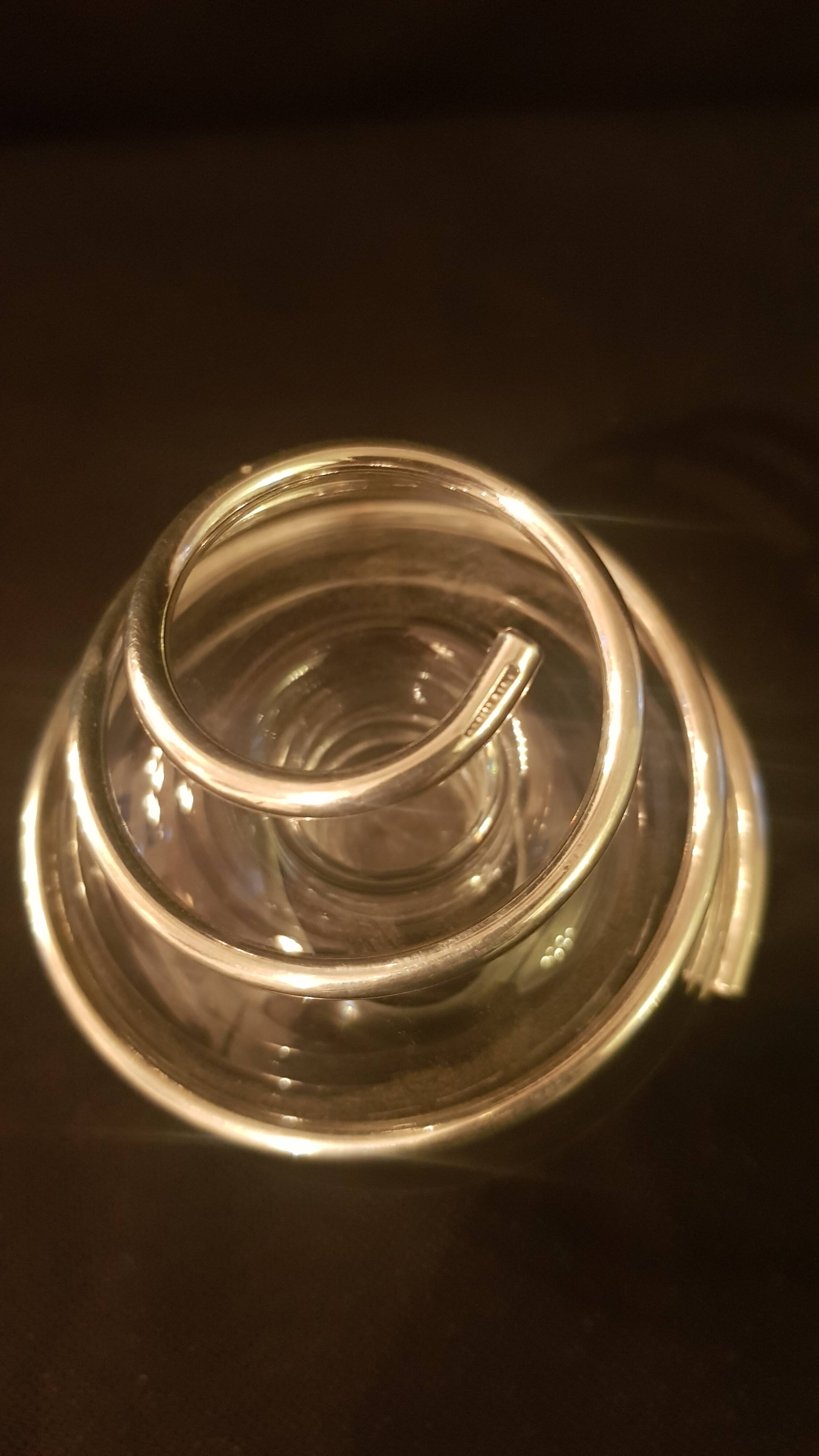 Round glass candle holder with silver-plated metal spiral.