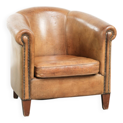 Fauteuil club en peau de mouton vintage fini avec des clous décoratifs.