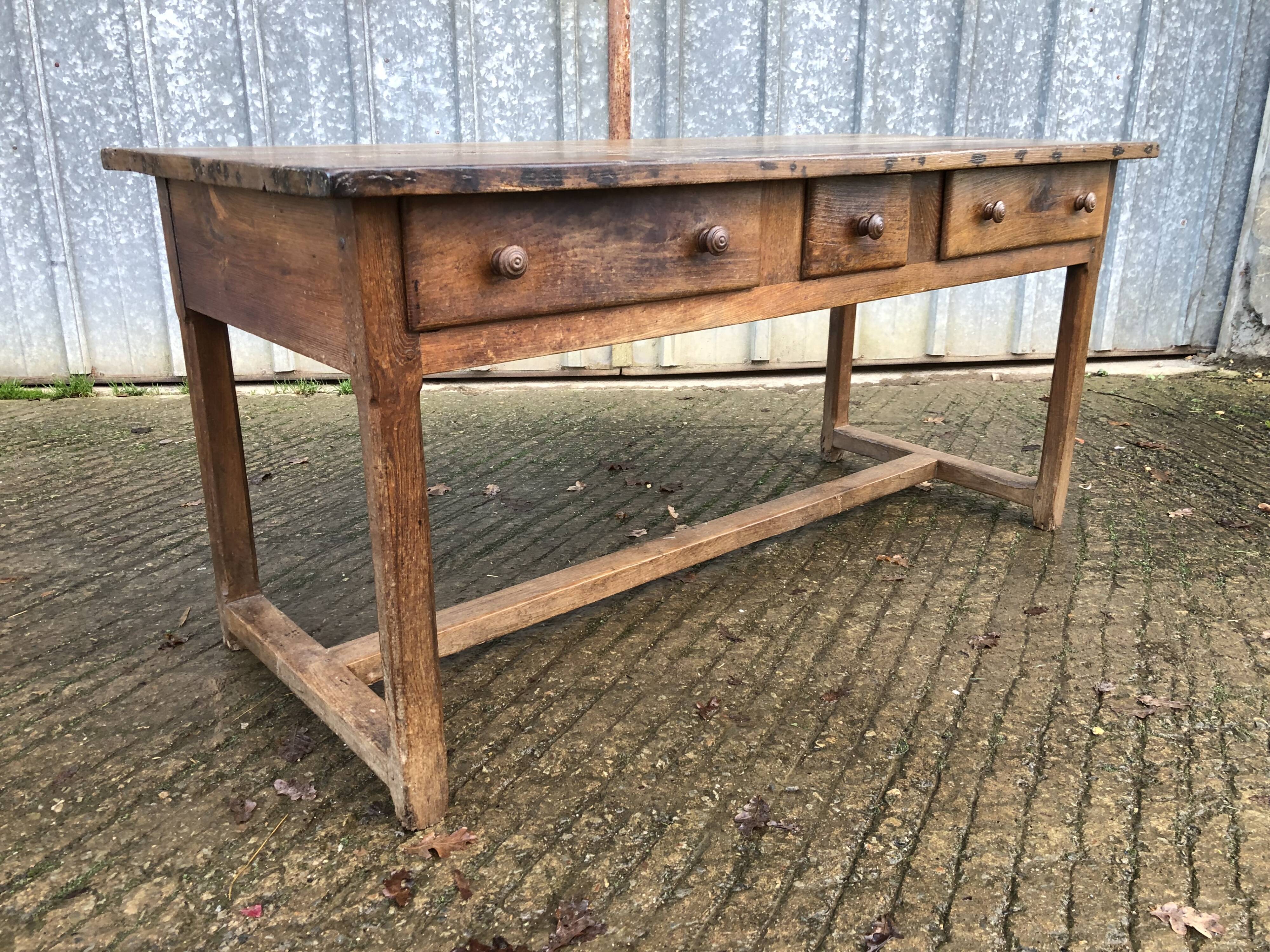 Old chestnut table with 3 front drawers and a cat bar.