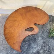 Mid-century coffee table with a palette shape and splayed legs.