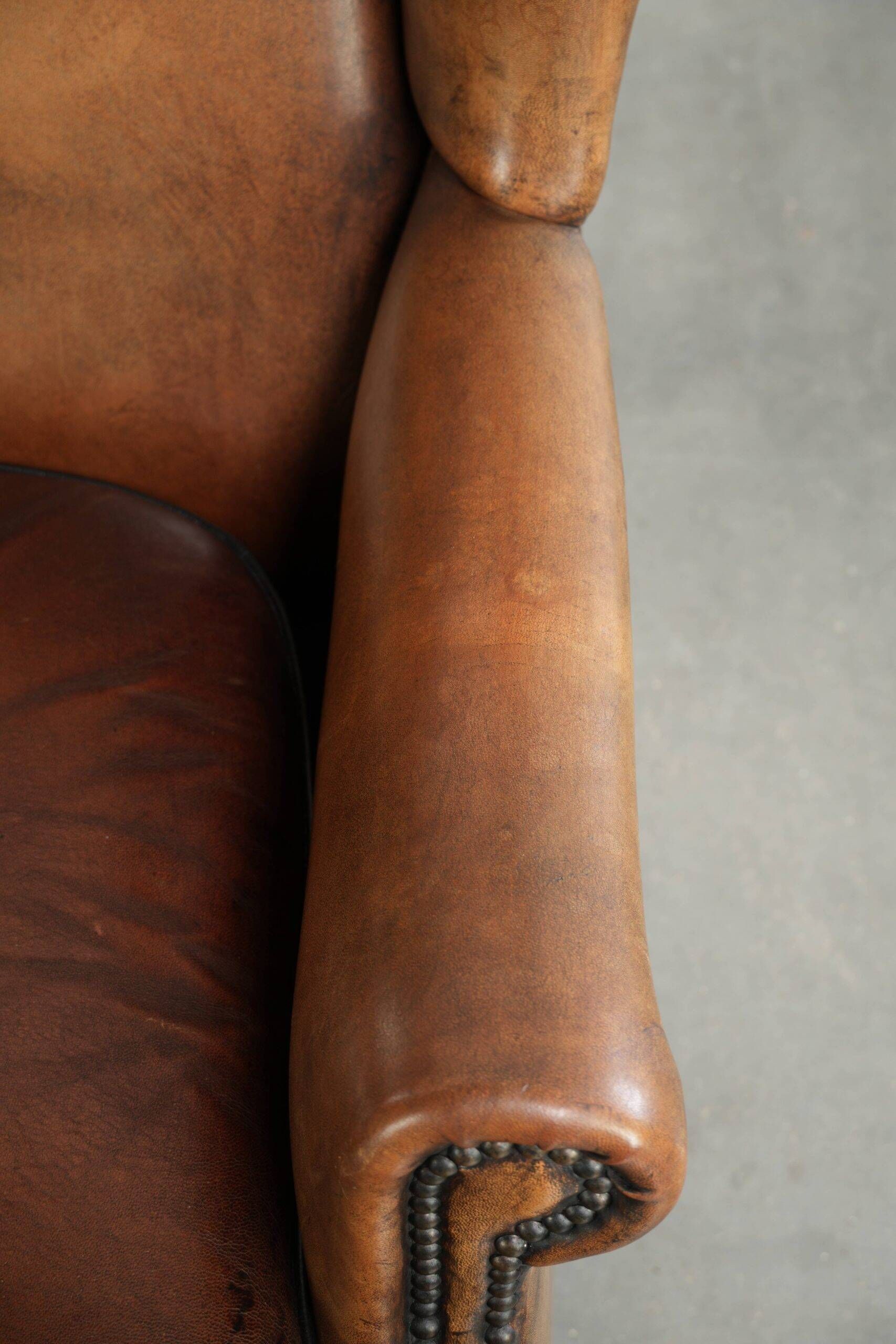 Sheepskin wingback armchair with patina finished with decorative nails