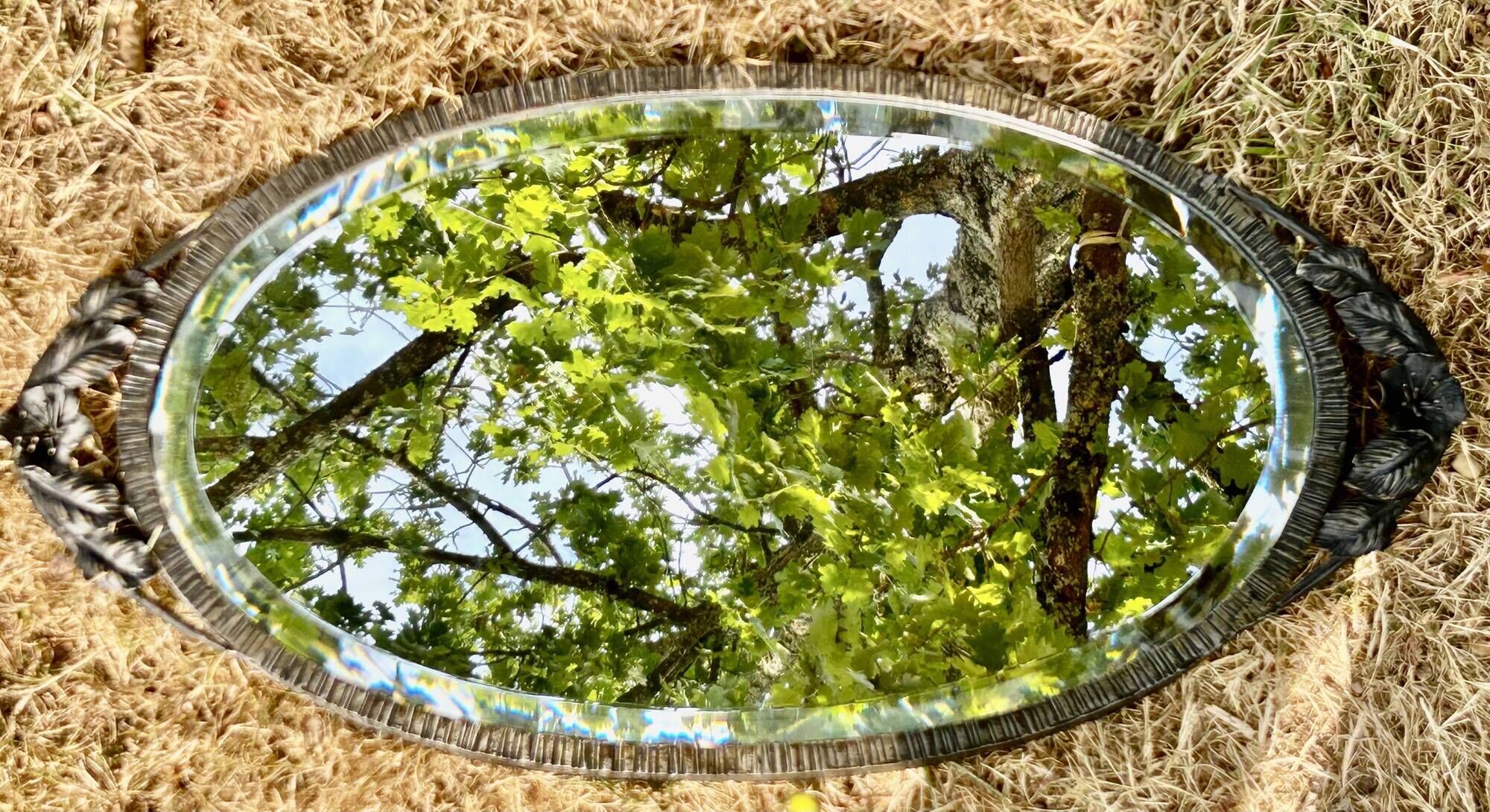 Bevelled oval mirror, richly crafted Art Deco wrought iron.