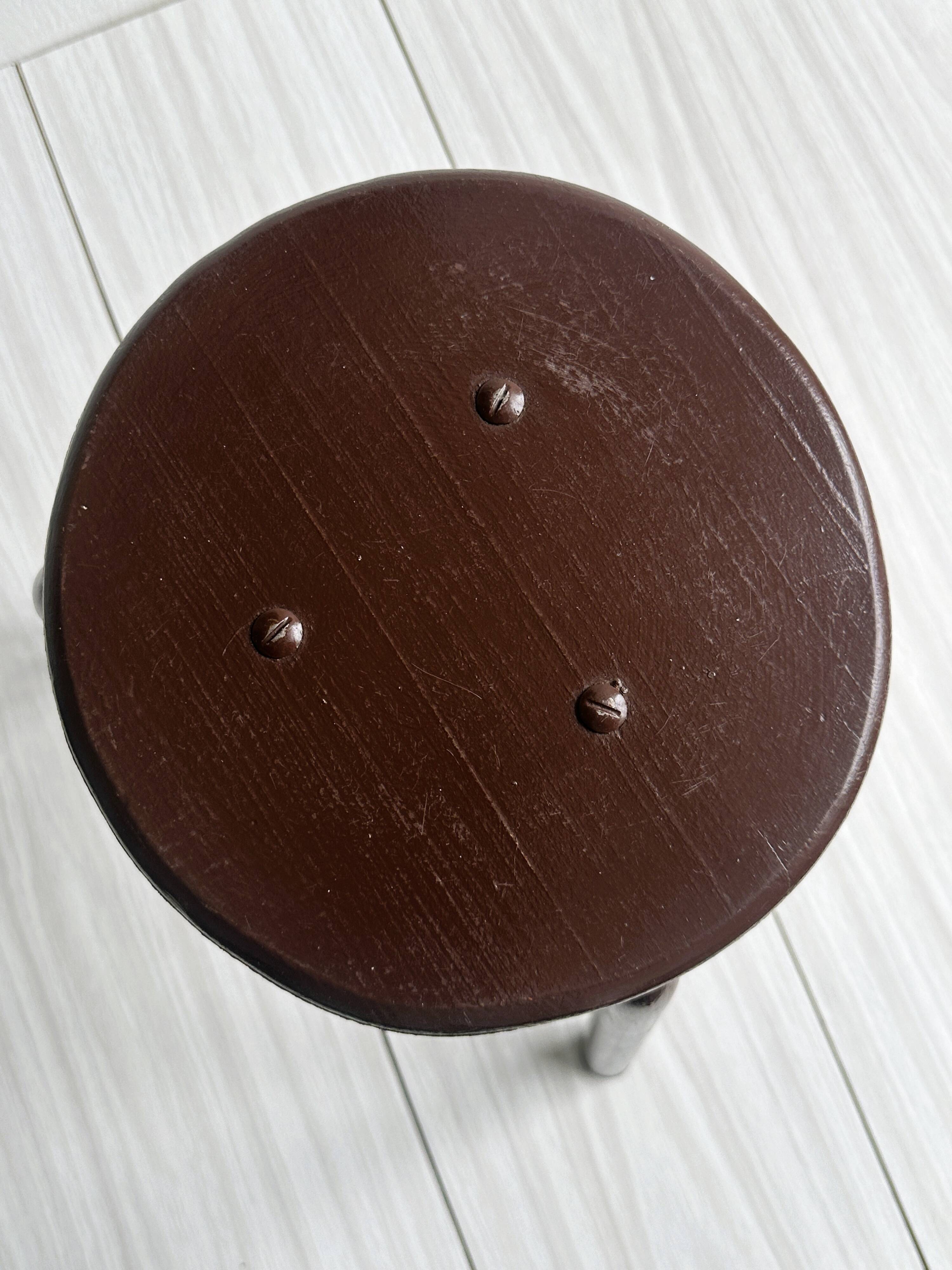Dark brown metal stool, minimalist three-legged design