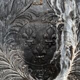 huge old fireplace plate has decoration of angels, crown and fleurs-de-lis