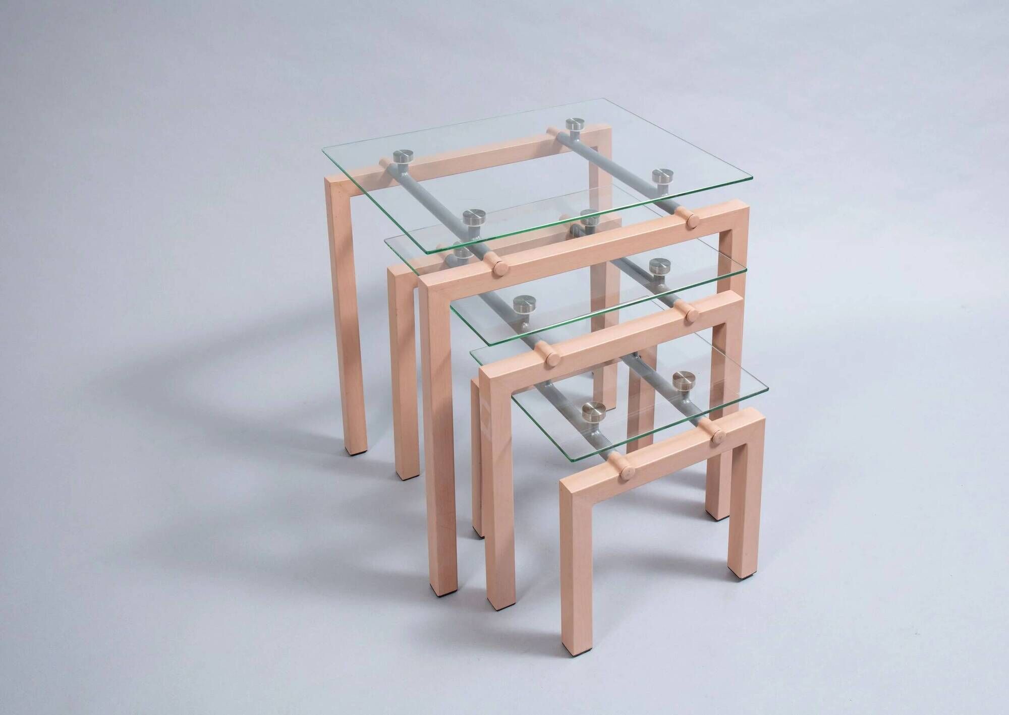 Three nesting tables from the 90s made of painted metal and tempered glass.