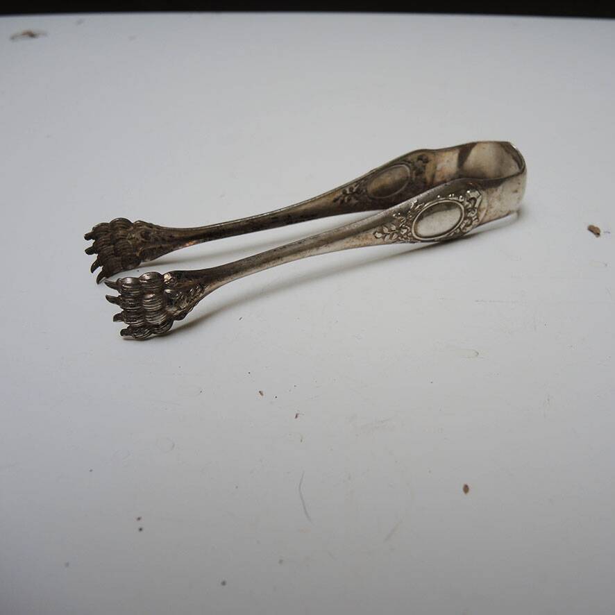 Antique metal sugar tongs in the shape of a lion's paw.