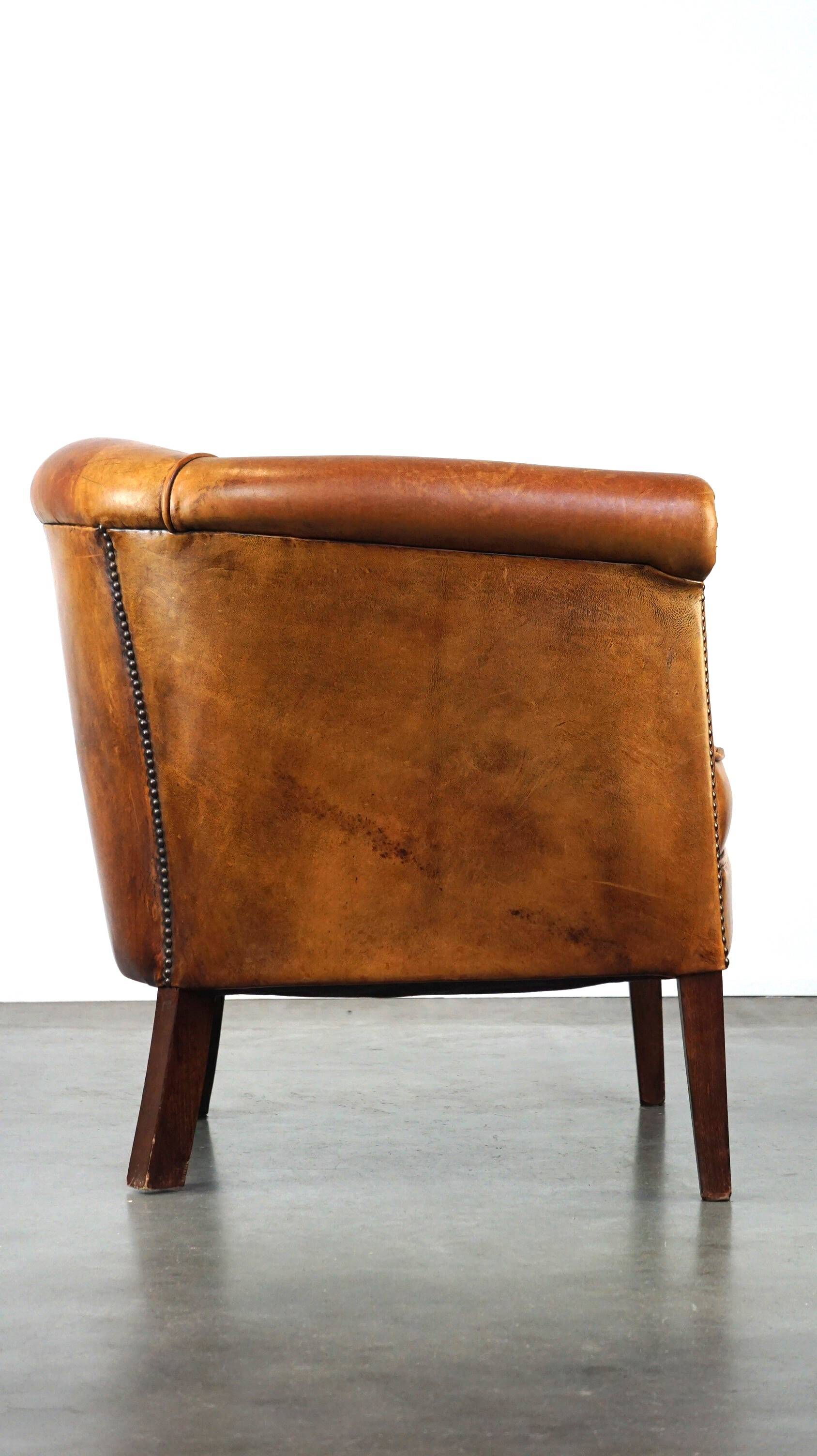 Neat and subtle sheepskin club chair, finished with decorative studs and a fixed seat cushion