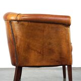 Neat and subtle sheepskin club chair, finished with decorative studs and a fixed seat cushion