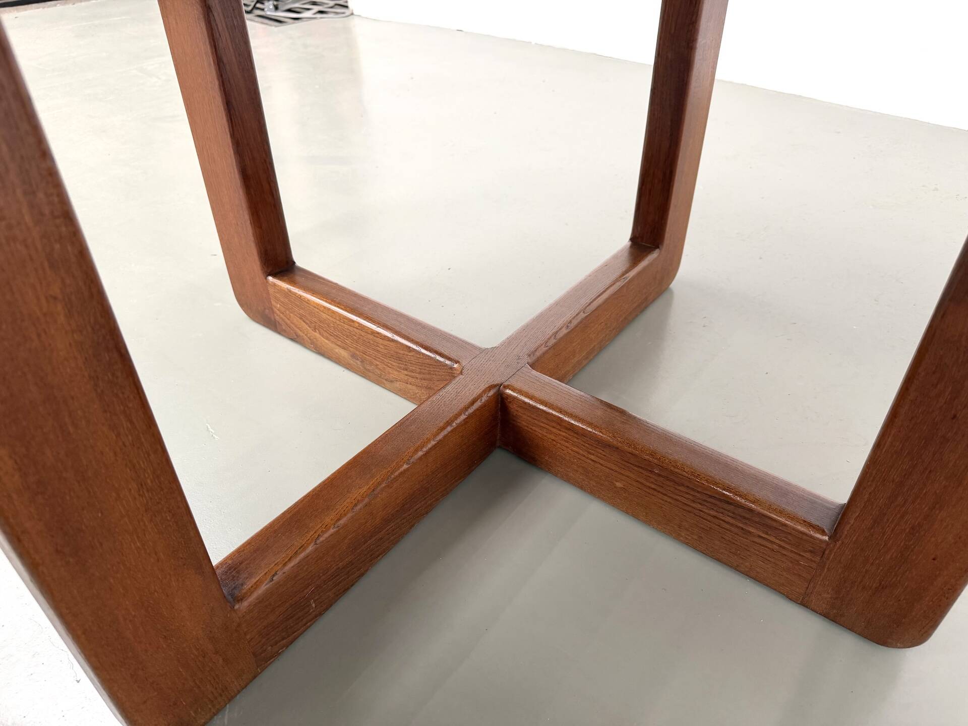 Modernist round table in solid elm, crossed legs.