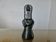 Matte black ceramic sculpture representing a female tribal figure.