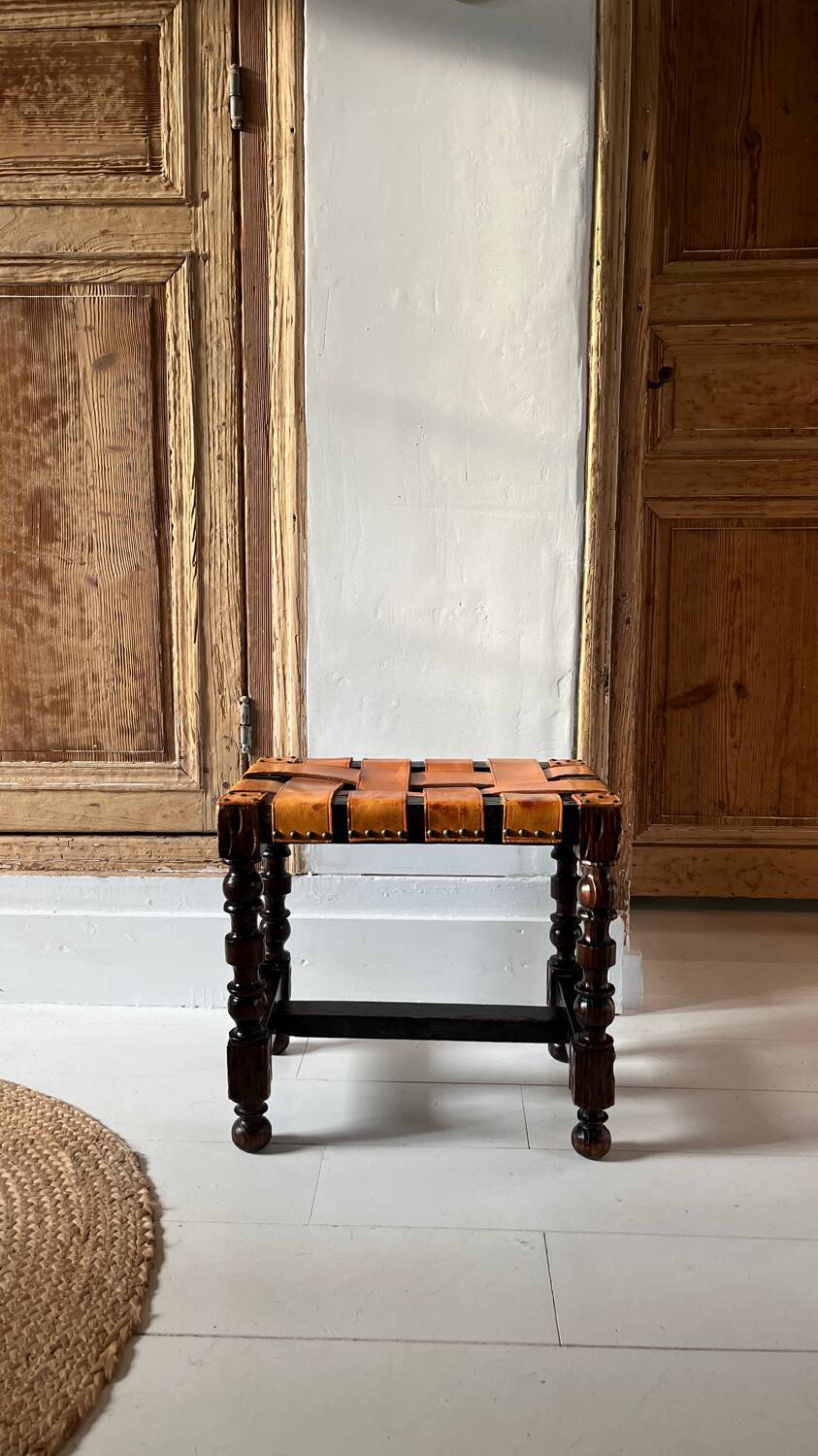 Antique turned wooden stool with woven leather.