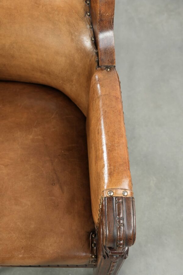 Fauteuil ancien en peau de mouton et bois avec des clous décoratifs.