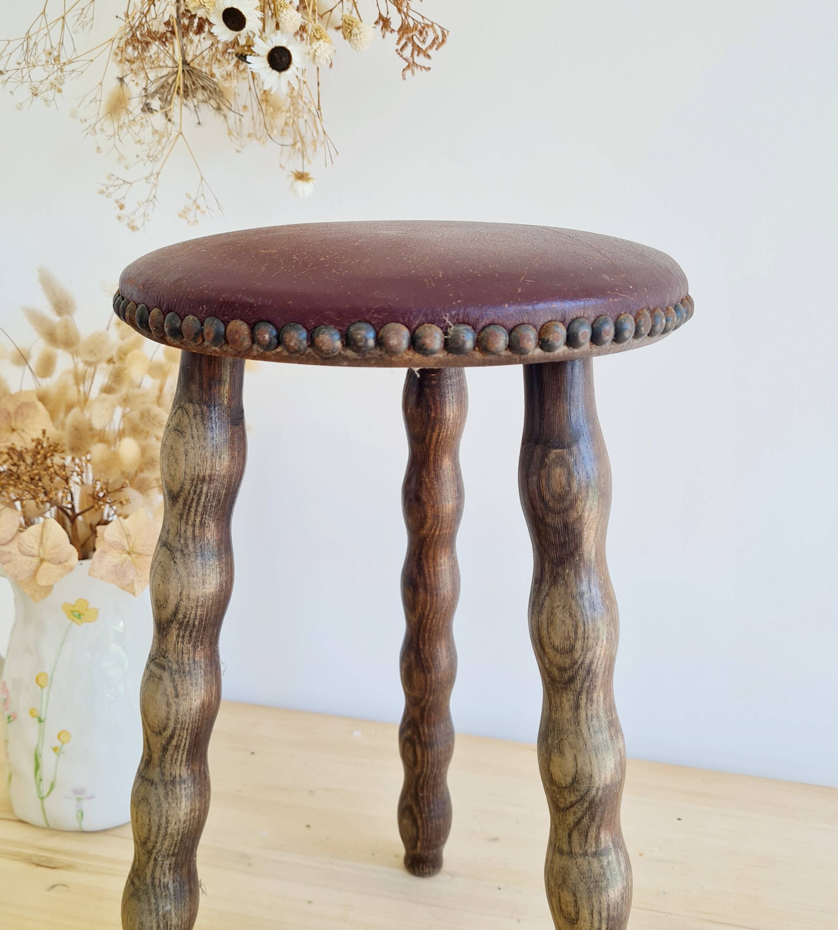 Antique tripod stool with turned wooden legs and leather seat.