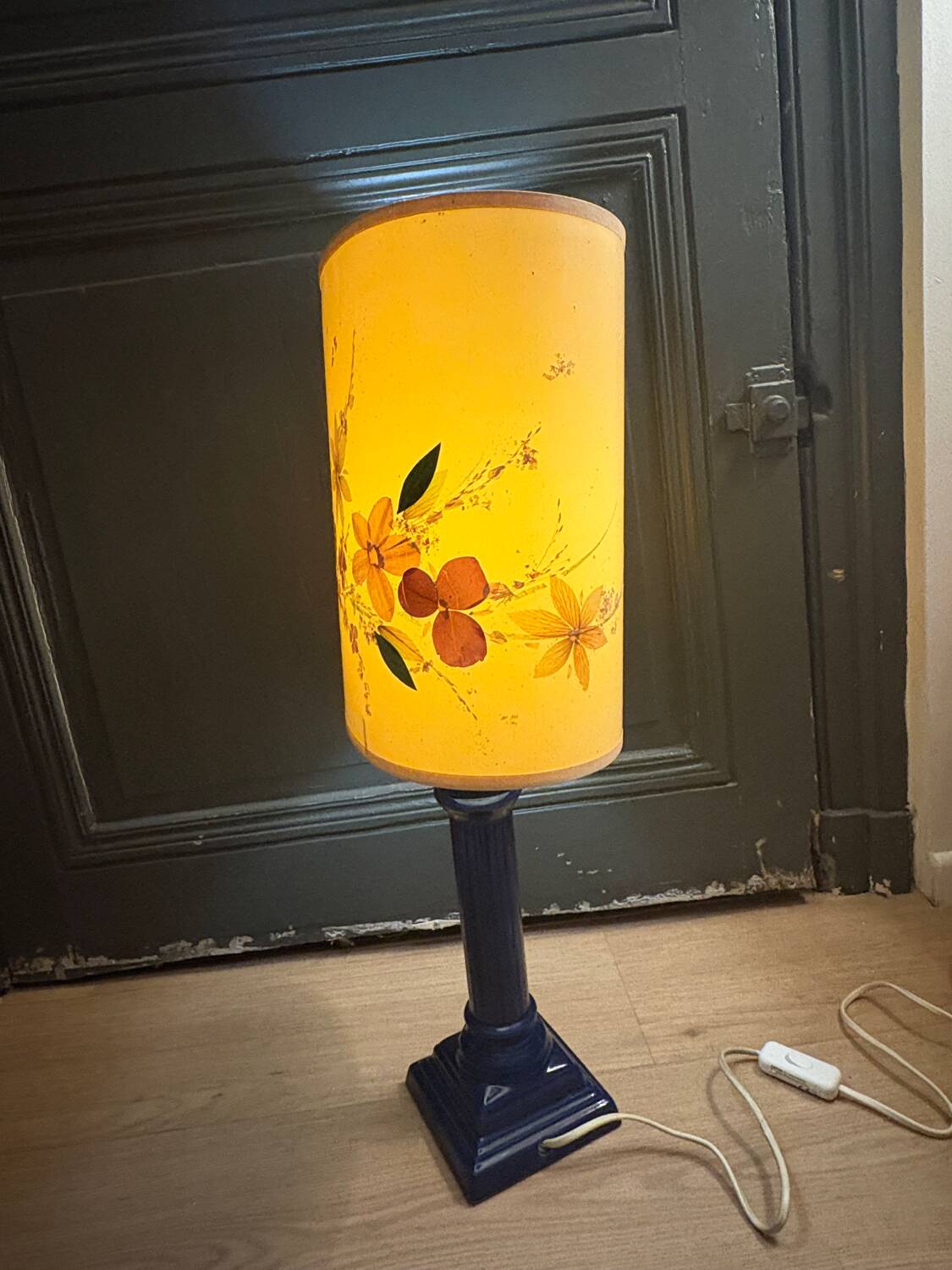 Corinthian column lamp base in blue with a lampshade of dried flowers.
