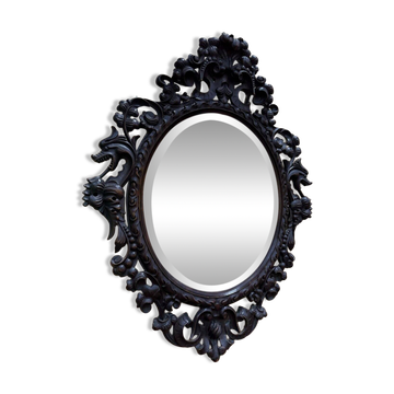 Oval mirror in carved wood with dragon heads.