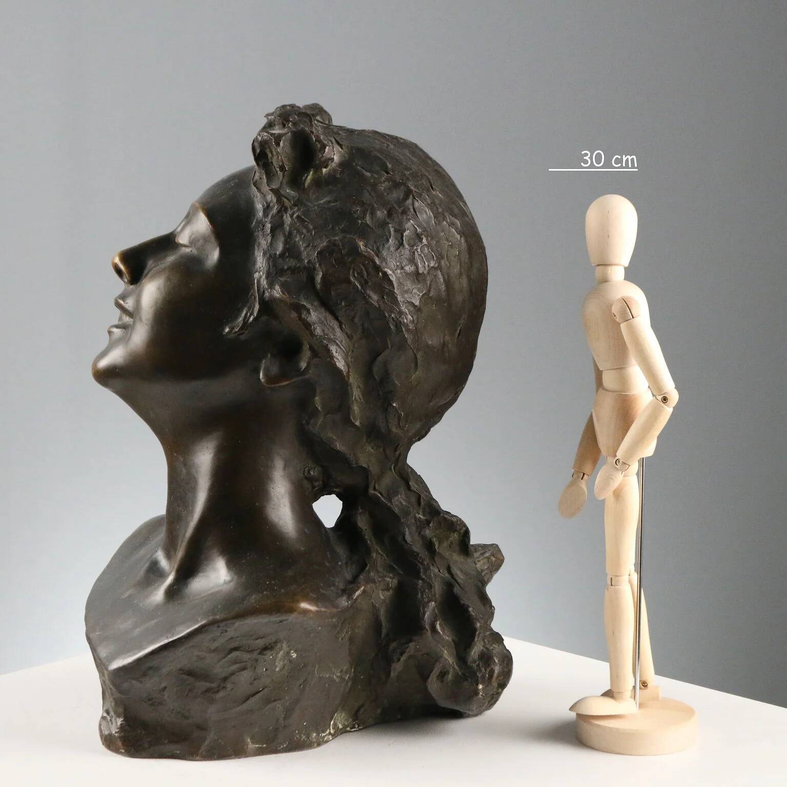 Ancient sculpture of a young woman's face in bronze, 19th-20th century.