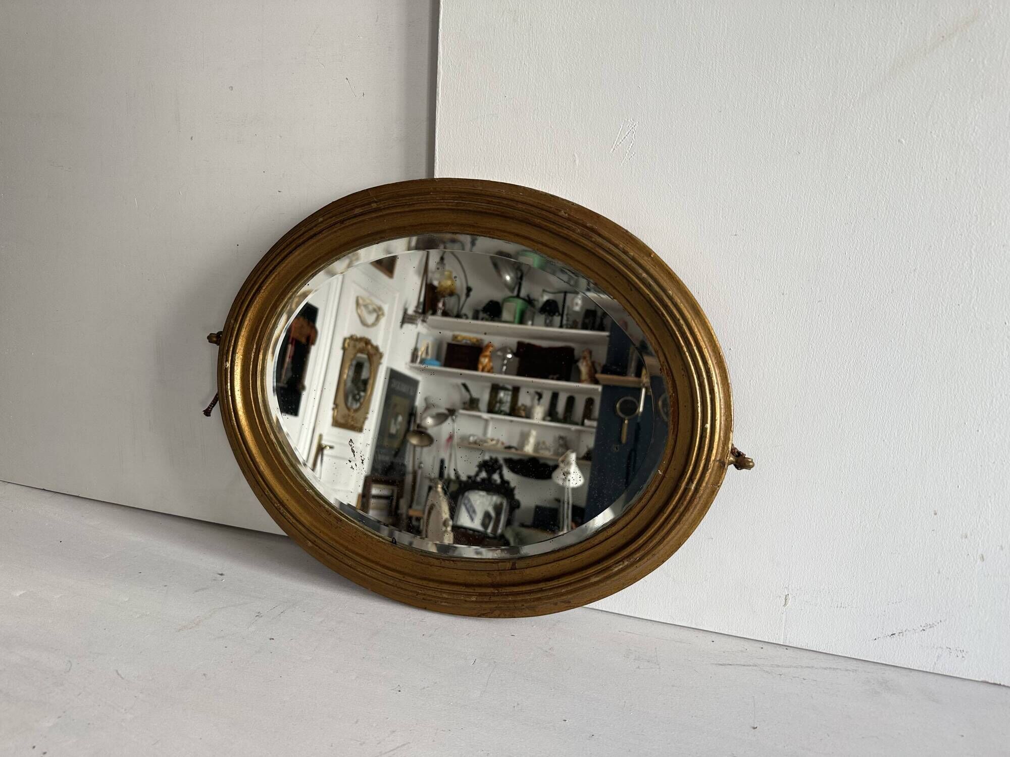 Antique oval mirror in gilded wood, bevelled mercury glass, 19th century.