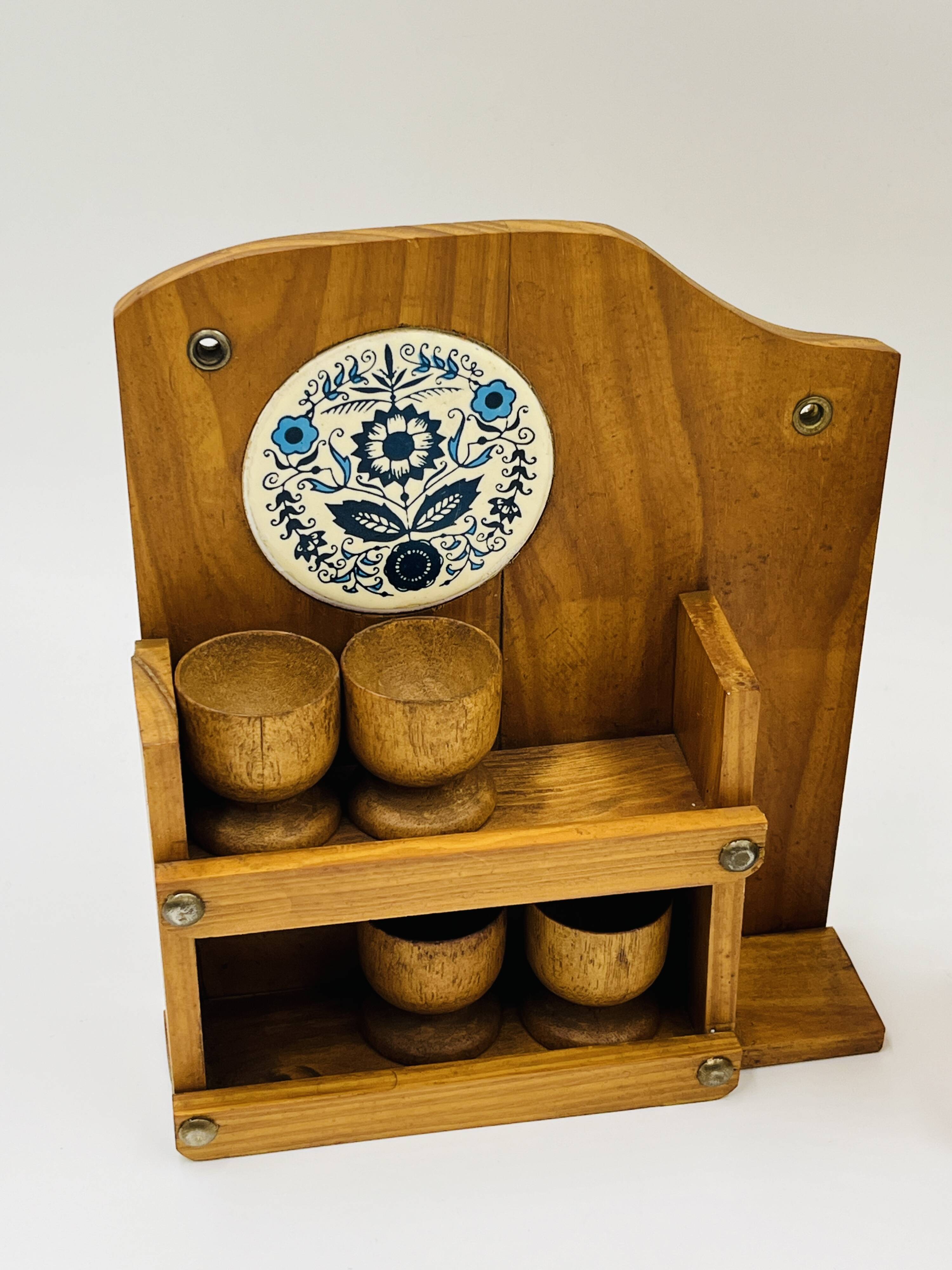 Wall-mounted egg cup holder and wooden utensil holder.