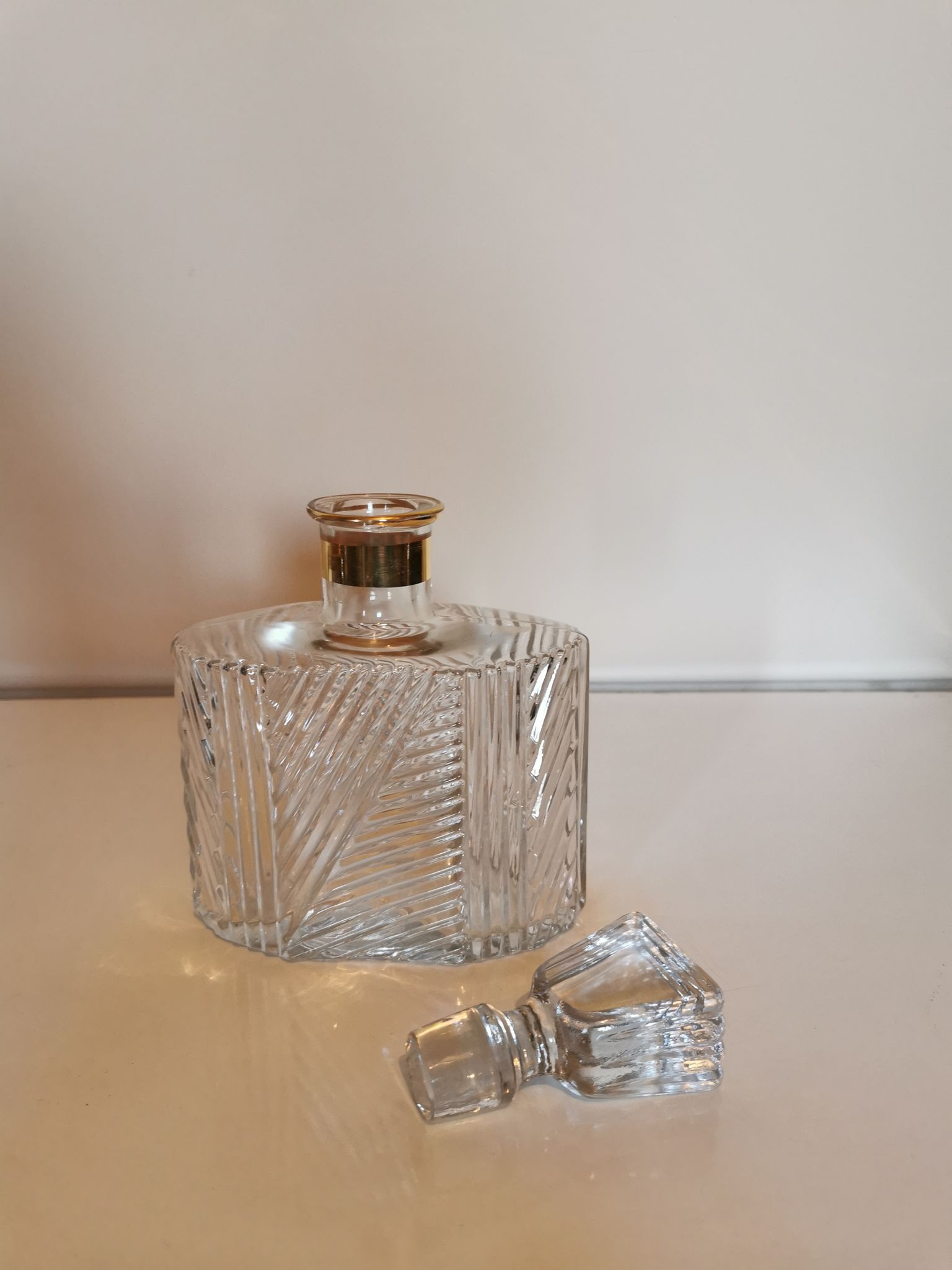 Cut glass carafe with a gold band on the neck.