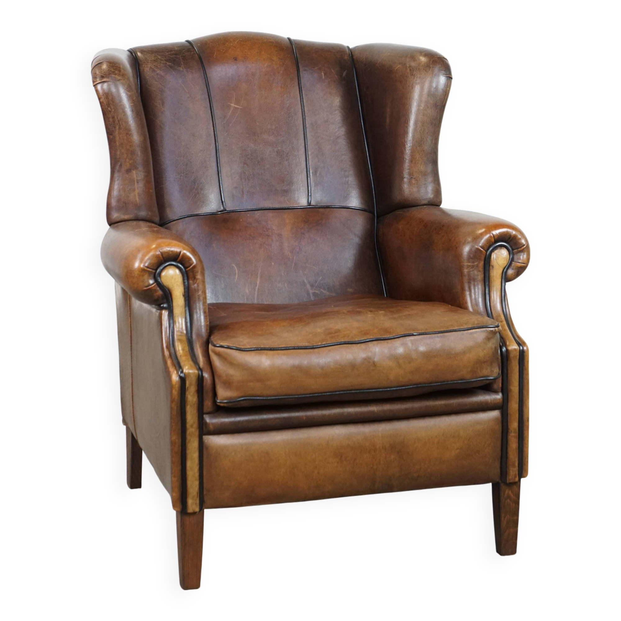 Vintage sheepskin wingback chair finished with black piping