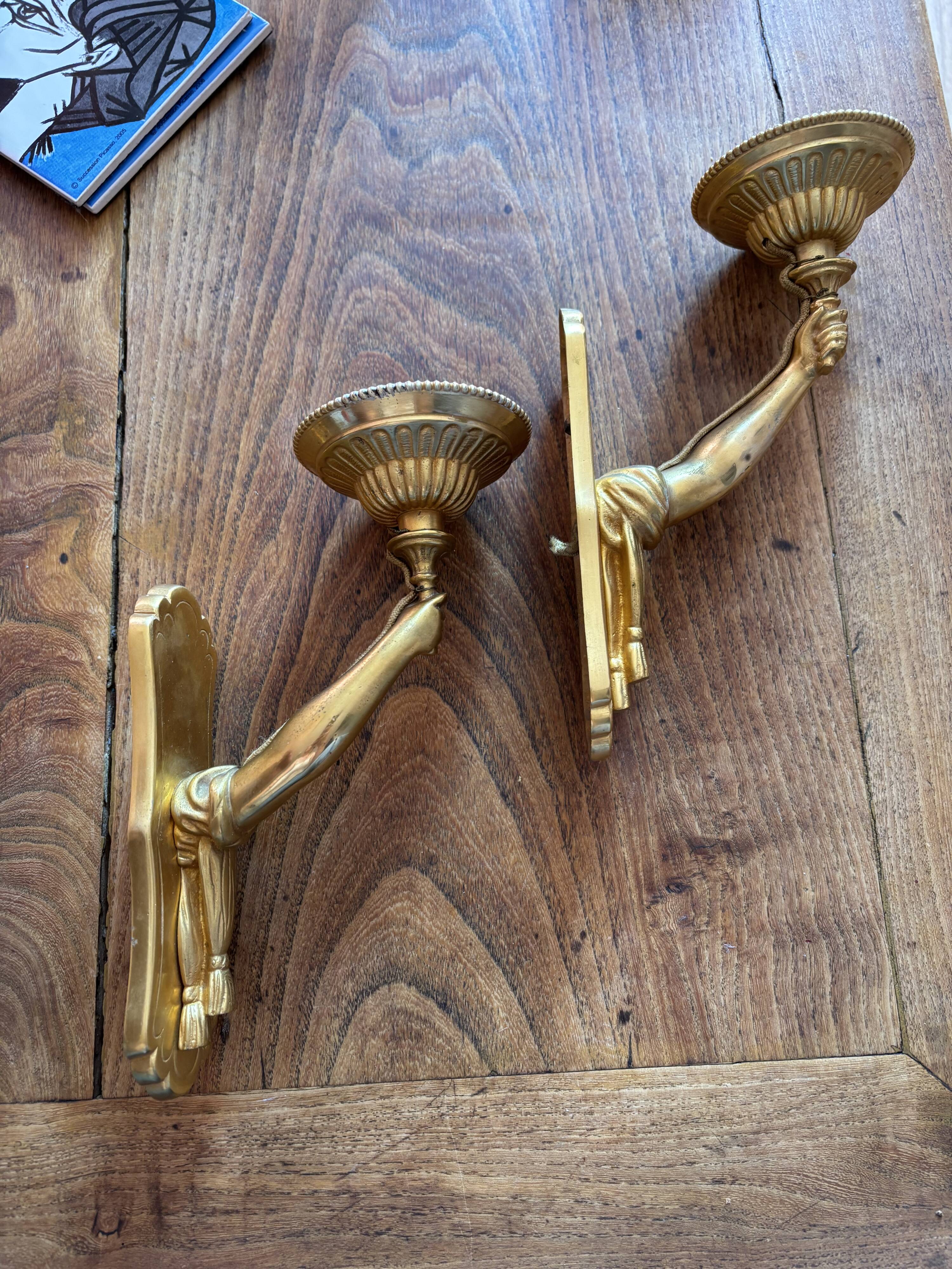 Pair of bronze wall sconces with outstretched arms and hands
