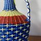 Vintage glass bottle and plastic scoubidou weaving.