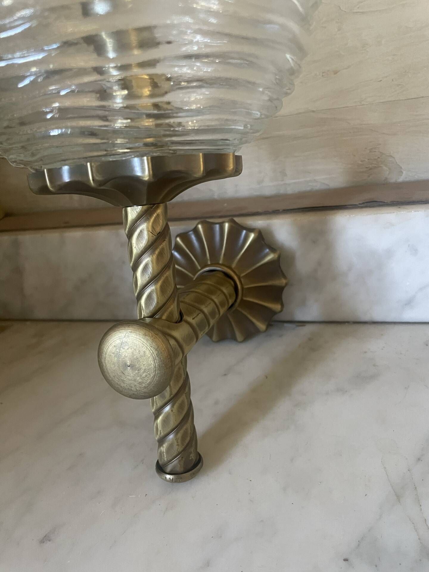 Pair of neoclassical wall sconces in twisted brass and ribbed glass.