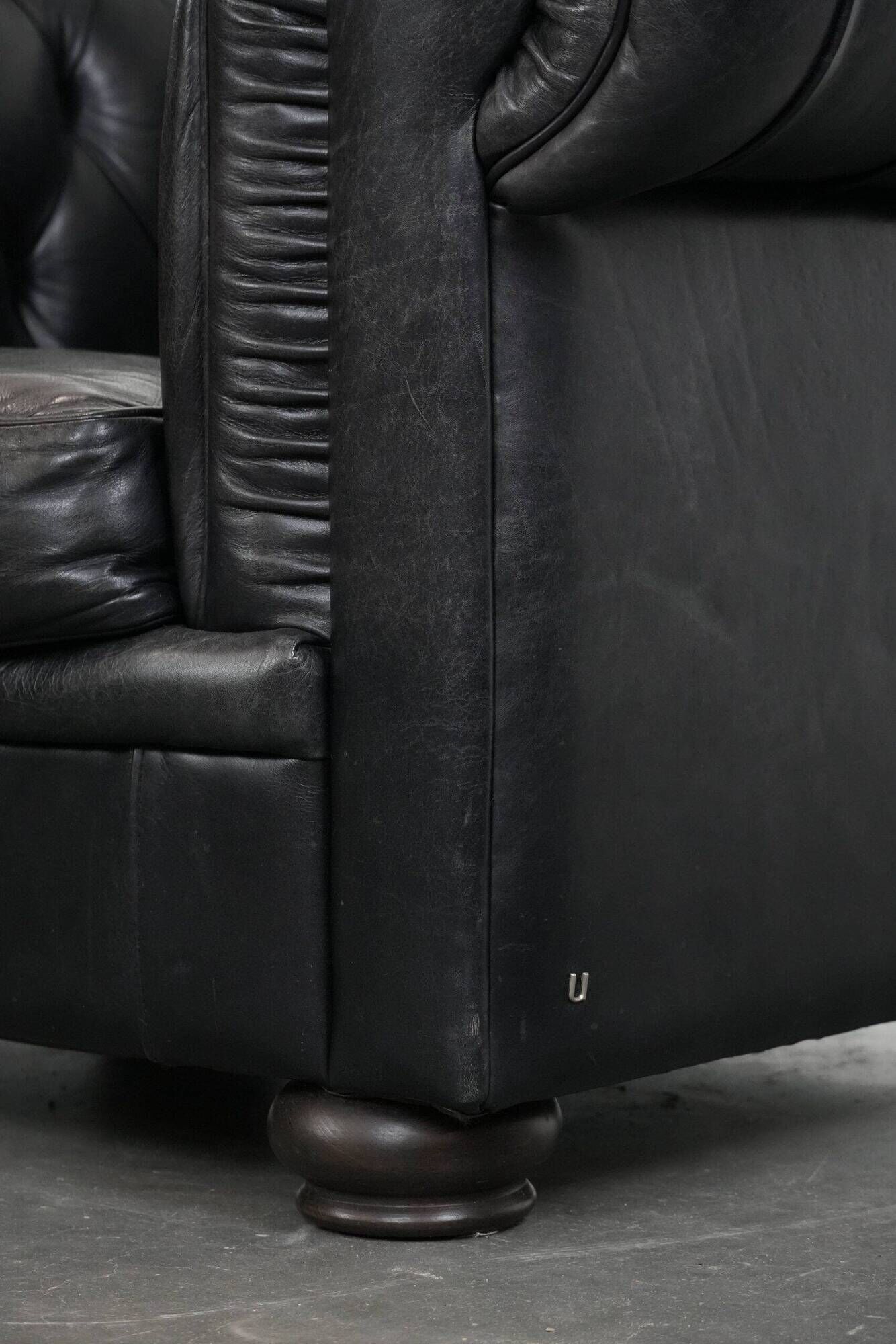 Set of a black cowhide leather Chesterfield armchair and matching ottoman