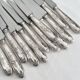 12 antique silver-plated knives with acanthus shell decoration and stainless steel blades.