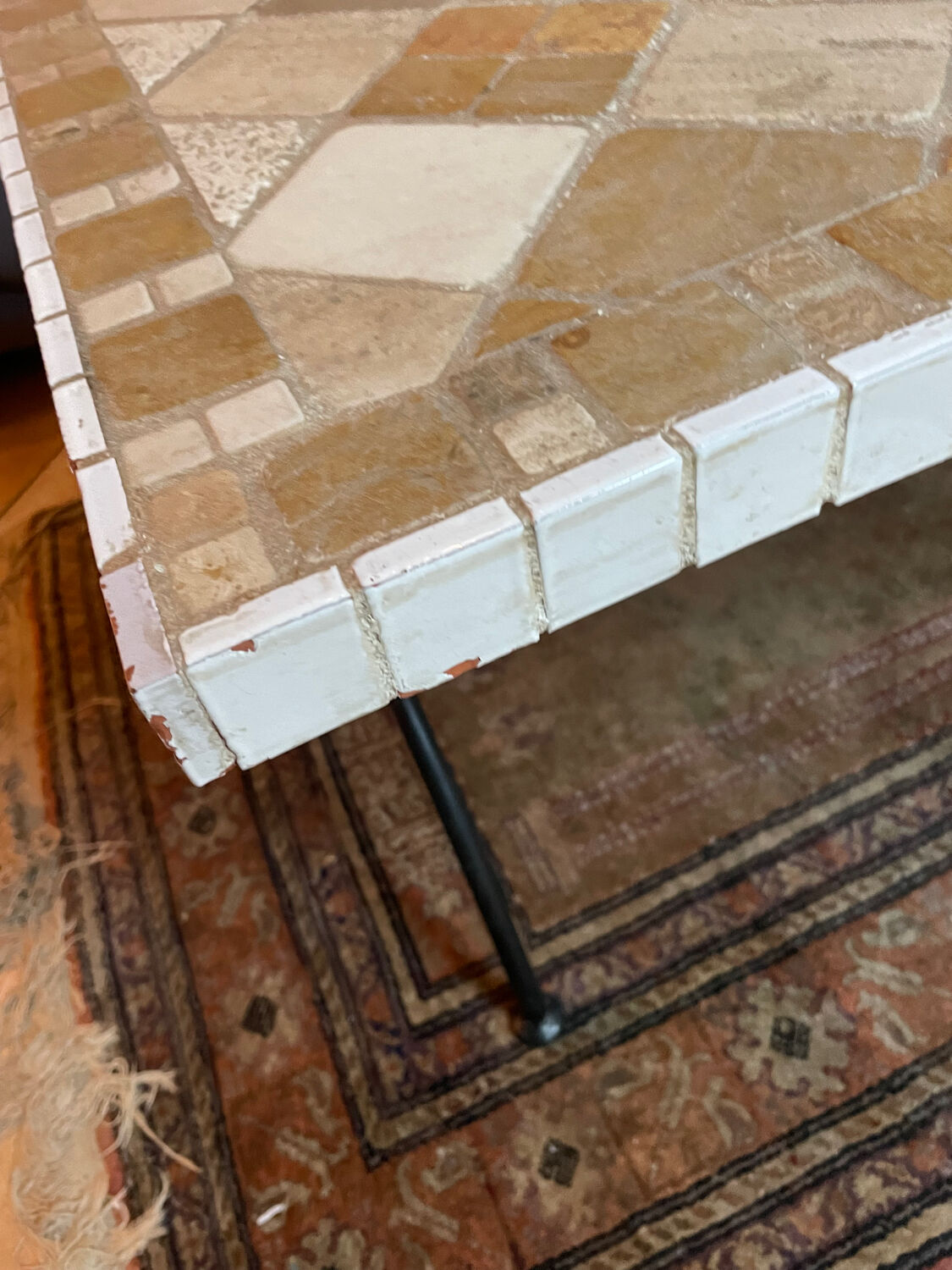 Beige ceramic coffee table with black metal legs.