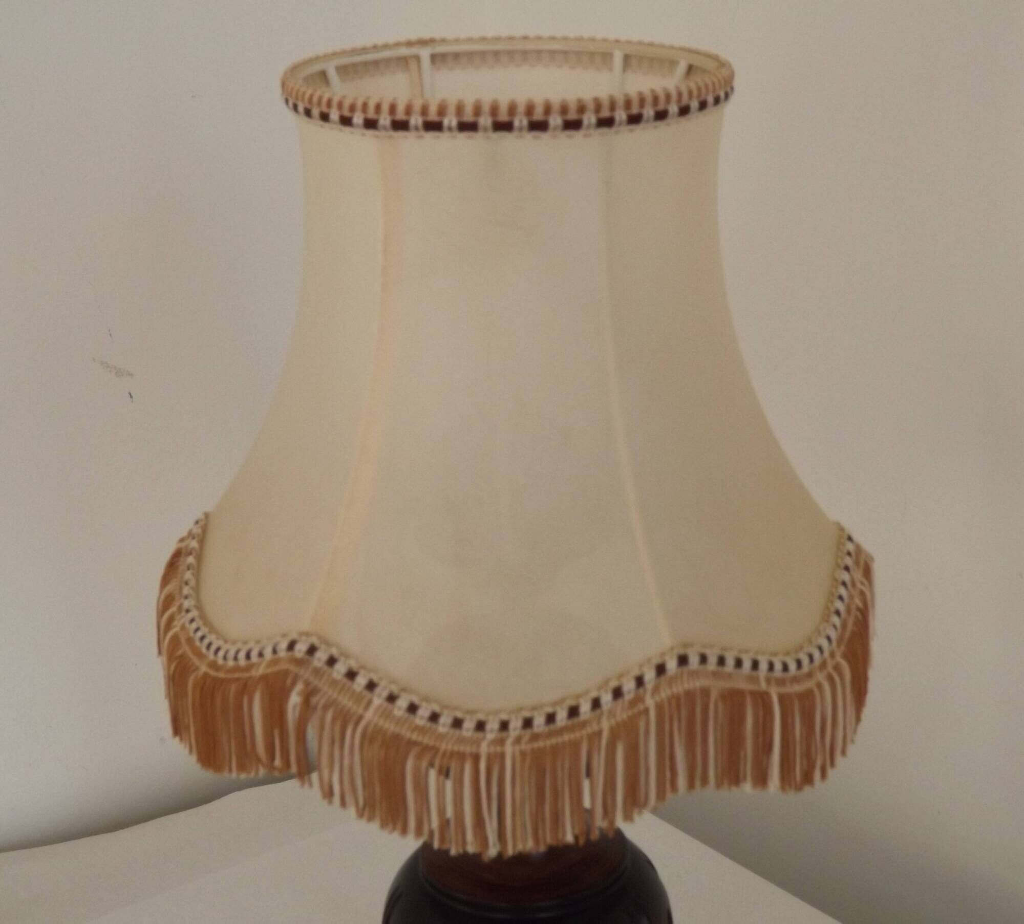 Mid-century French table lamp made of turned carved wood with a fringed shade.