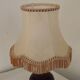 Mid-century French table lamp made of turned carved wood with a fringed shade.