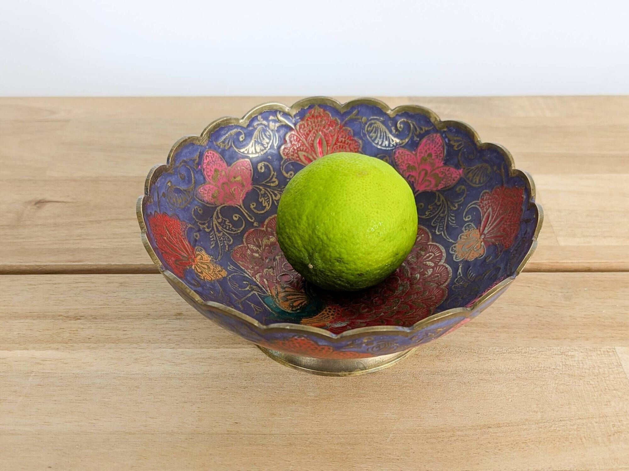 Vintage brass bowl with peacock motif, painted enamel, scalloped edge on a pedestal.