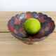 Vintage brass bowl with peacock motif, painted enamel, scalloped edge on a pedestal.