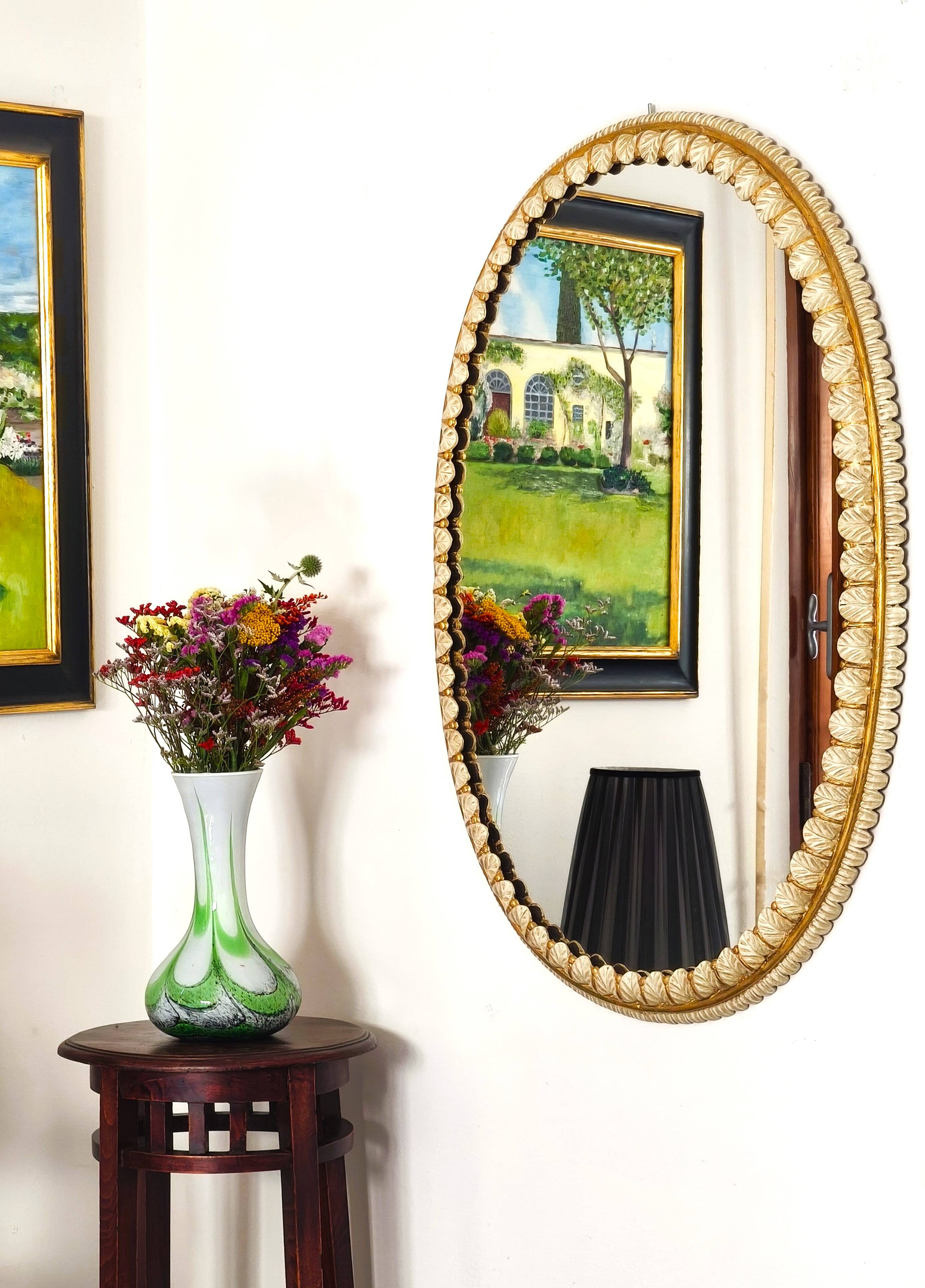 Large oval Florentine mirror in carved wood and gilded with gold leaf.