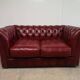Red two-seater chesterfield sofa