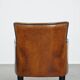 Cognac-colored sheepskin armchair with black piping and decorative nails