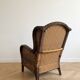Vintage armchair in rattan and wicker with beige cushion.